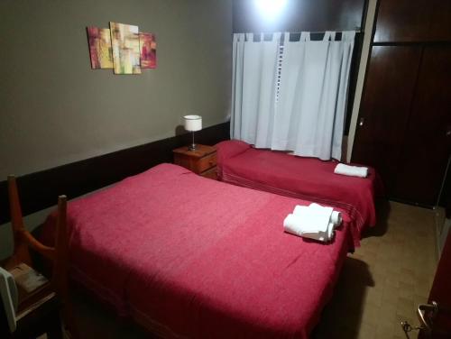 two beds in a room with red sheets and towels at Hospedaje Champaqui in Santa Rosa de Calamuchita