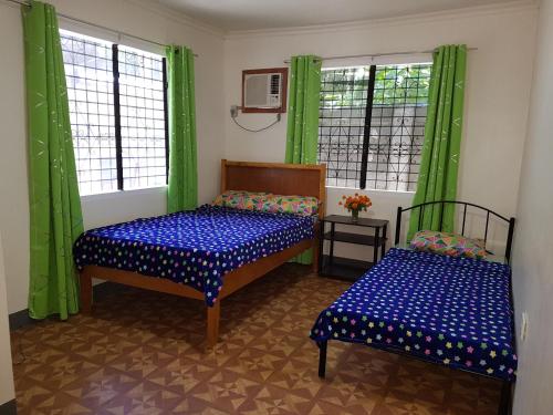 two beds in a room with green curtains and windows at OMG Guesthouse Room for 4 in Licup