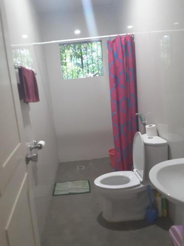 a bathroom with a toilet and a red shower curtain at OMG Guesthouse Room for 4 in Licup
