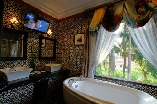 a bathroom with a tub and two sinks and a television at Kinta Bali Villa in Ipoh