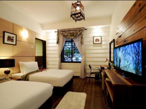 a hotel room with two beds and a flat screen tv at Kinta Bali Villa in Ipoh