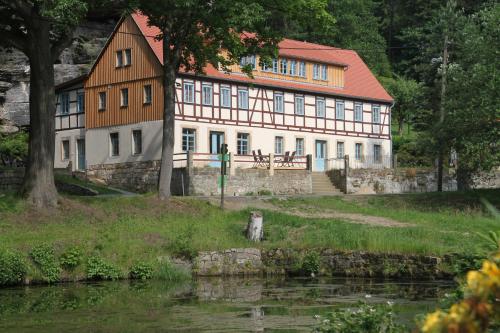 a large building next to a body of water at Ferienwohnungen Felsenkeller Bielatal in Bielatal