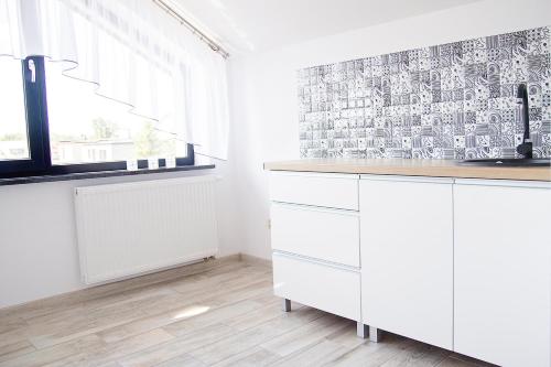 une cuisine avec des placards blancs et une fenêtre dans l'établissement Silver Apartments, à Sarbinowo