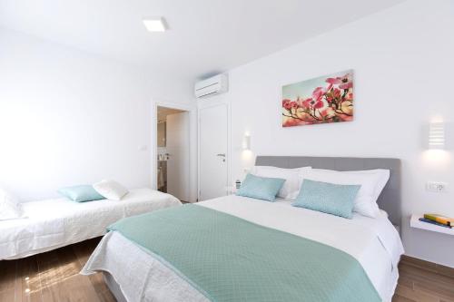 a white bedroom with two beds and a painting on the wall at Villa Magdalena in Porat