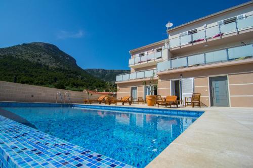 a swimming pool in front of a building at Villa Nikola - pool side apartments in Bol