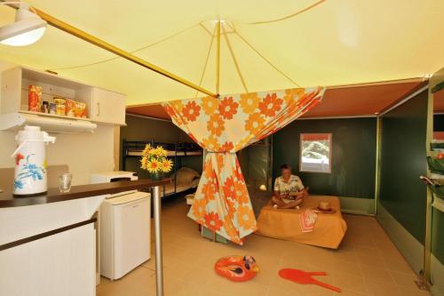 un homme assis sur un canapé dans un salon dans l'établissement Camping la Plage Lot Vallée de la Dordogne Rocamadour, à Meyronne