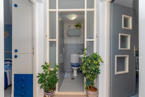 a bathroom with a toilet and two potted plants at Apartman Sunrise in Vela Luka