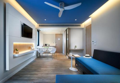 a living room with a blue couch and a ceiling at OZO Phuket in Kata Beach