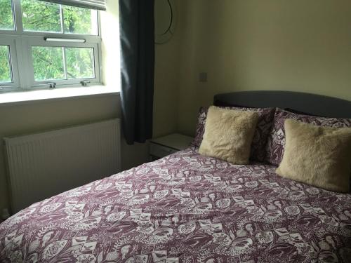 1 cama con manta morada y almohadas junto a una ventana en Superb Peaceful 1 bed apartment in St George., en Bristol