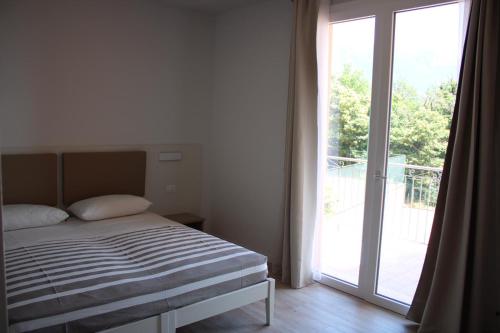 een slaapkamer met een bed naast een glazen schuifdeur bij Appartamenti Morele in Tignale