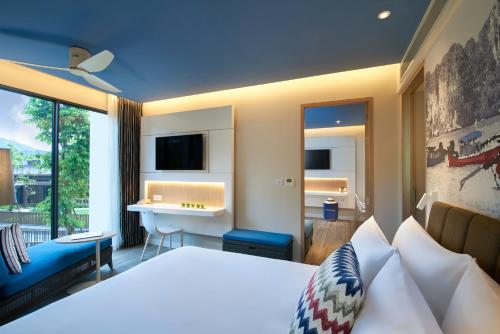 a bedroom with a bed and a desk and a sink at OZO Phuket in Kata Beach