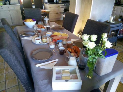 een tafel met borden en bloemen en een laptop erop bij Votre Horizon in Aywaille