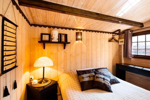 a bedroom with a bed in a room with wooden walls at VILLA ZENITH Hostel - LA MAISON in Lacanau