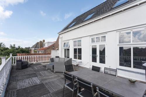 eine Terrasse mit einem Tisch und Stühlen auf einem weißen Haus in der Unterkunft B&B de Lijsterhof in Domburg