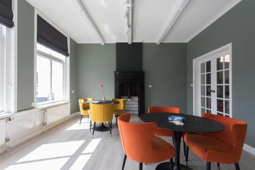 a dining room with a black table and orange chairs at B&B de Lijsterhof in Domburg