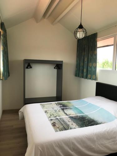 sypialnia z białym łóżkiem i oknem w obiekcie Vakantiewoning De Zandkorrel w mieście Middelkerke