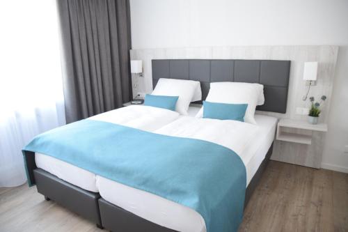 a bedroom with a large bed with blue pillows at Hotel Thode in Dahme
