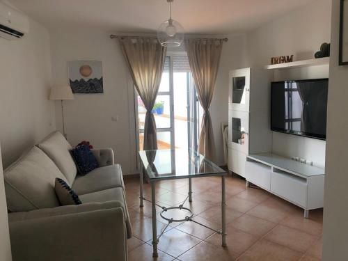 ein Wohnzimmer mit einem Glastisch und einem TV in der Unterkunft ATICO SAN MARCOS in El Puerto de Santa María