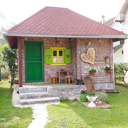 una pequeña casa con una puerta verde y una mesa en Etno apartman Tajna, en Gornja Toplica
