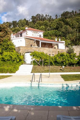 a swimming pool in front of a house at Quinta Das Rossadas in Cinfães