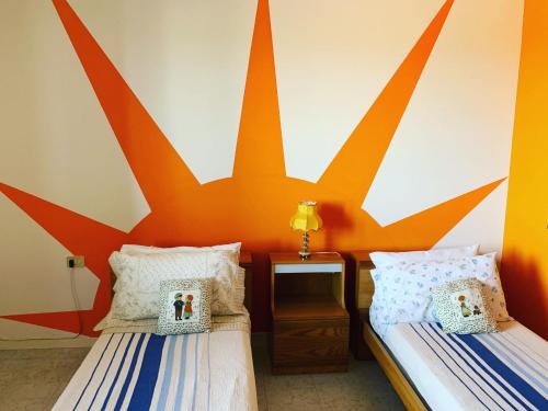 two beds in a room with an orange wall at B&B Portobello in Torrevecchia Teatina