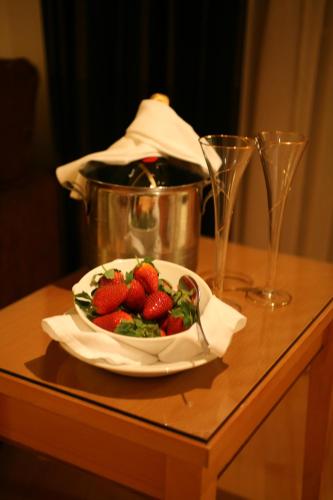 a bowl of strawberries on a table with two glasses at The Fairview Boutique Hotel in Killarney