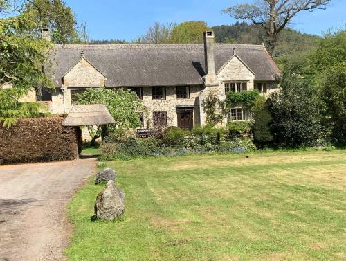 a house with a rock in front of a yard at Linhay -Farm Cottage in Sidmouth