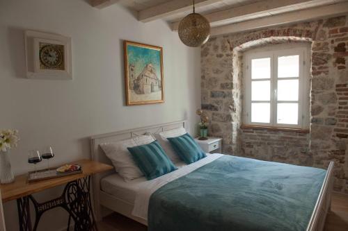 a bedroom with a bed and a desk and a window at Sobe Bile in Pag