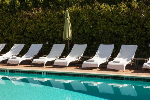 a group of chairs and an umbrella next to a pool at La Maison Hotel - Adults Only in Palm Springs