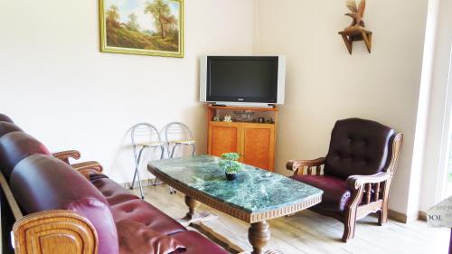 a living room with a couch and a table and a tv at Hőforrás Wellness Vendégház in Egerszalók