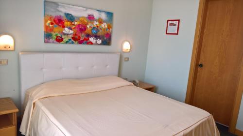 a white bed in a room with a painting on the wall at Hotel Ristorante alla Campagna in San Giovanni Lupatoto