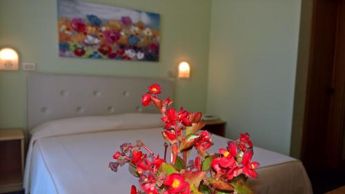 a vase with red flowers on a table in a bedroom at Hotel Ristorante alla Campagna in San Giovanni Lupatoto