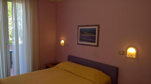 a bedroom with a bed and two lights on the wall at Hotel Ristorante alla Campagna in San Giovanni Lupatoto