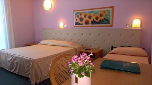 a hotel room with two beds and a table with flowers at Hotel Ristorante alla Campagna in San Giovanni Lupatoto