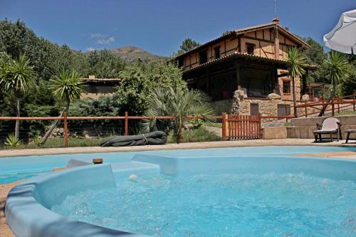 a swimming pool in front of a house at Complejo Rural La Coronilla in Jarandilla de la Vera