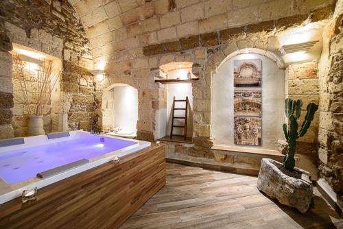 un ampio bagno con una grande vasca in un muro di pietra di Sacratum B&B Suite Spa a Mesagne