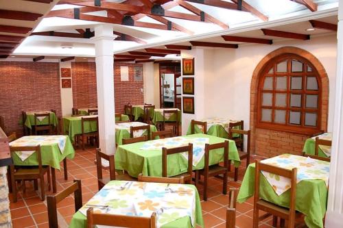 un restaurante vacío con mesas verdes y sillas en Casa Madrigal Hotel, en Pasto