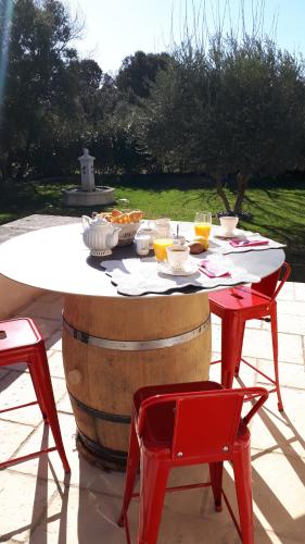 a table and two red chairs next to a wine barrel at la réveuse in Gordes