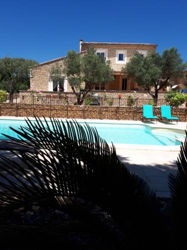 a swimming pool with two blue chairs in front of a house at la réveuse in Gordes