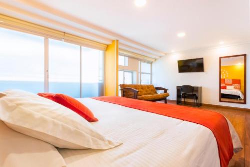 1 dormitorio con 1 cama blanca grande con almohadas rojas en Casa Madrigal Hotel, en Pasto