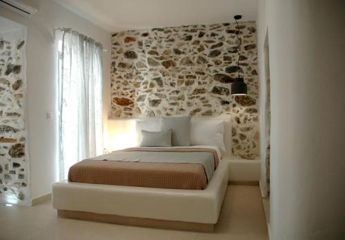 a bedroom with a bed with a stone wall at Kalypso House in Pera Gyalos