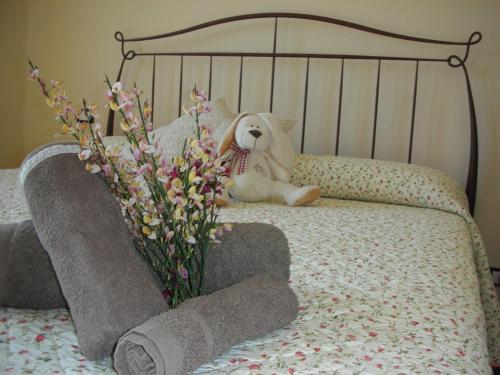 un osito de peluche sentado en una cama con flores en B&B Casacapraia, en Itri