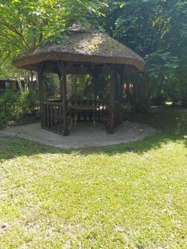 a wooden gazebo with a bench in the grass at Rába Part Apartman in Rábaszentmihály