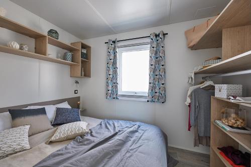 a small bedroom with a bed and a window at Le Clos des Genets in Quend