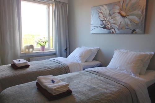 - 2 lits dans une chambre avec des serviettes et une fenêtre dans l'établissement City Apartment Haapaniemenkatu, à Kuopio