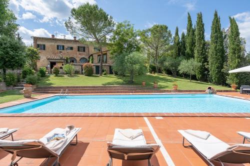 an outdoor swimming pool with chairs and a house at Il Palazzetto in Siena