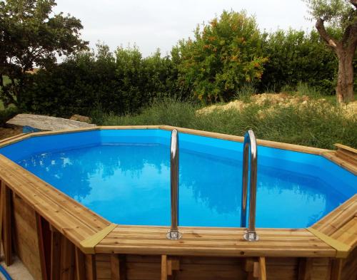a pool with a wooden deck and a blue swimming pool at "La Casa degli ulivi Art B&B" in Trecastelli