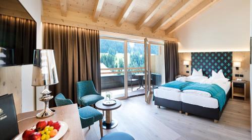 a hotel room with a bed and a desk and a room at Wellness Hotel Gran Risa***S in La Villa