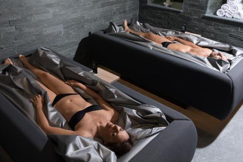 two women in underwear laying on beds in a room at Grand Hotel Castrocaro Longlife Formula in Castrocaro Terme
