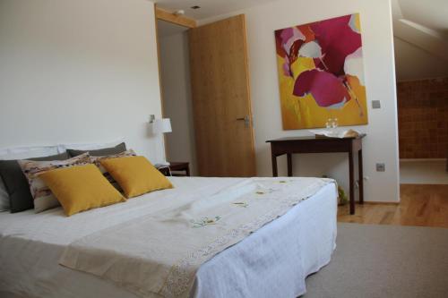 a bedroom with a large white bed with yellow pillows at Quinta de Fiães in Vilar de Maçada